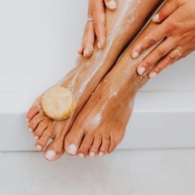 Close-up of a woman's feet being washed with organic soap for skincare and relaxation.